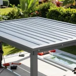 Installation einer Terrassenüberdachung mit stylischem Aluminiumdach und Handwerker im Garten.